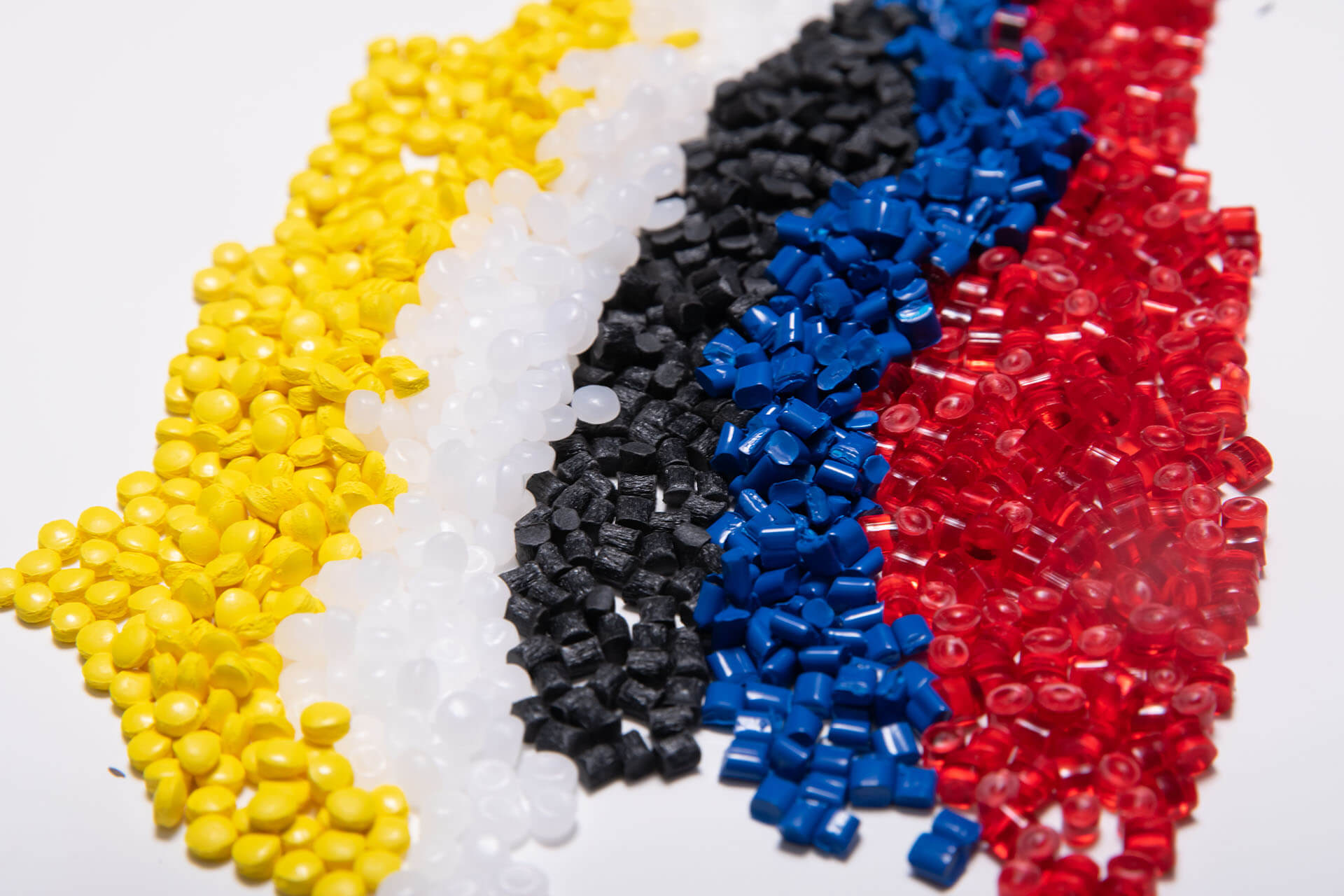 pile of injection molding resin pellets that are yellow white black blue red