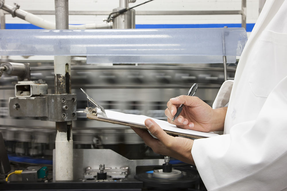 Closeup of a hand and a clipboard, technician checks inventory on a production line